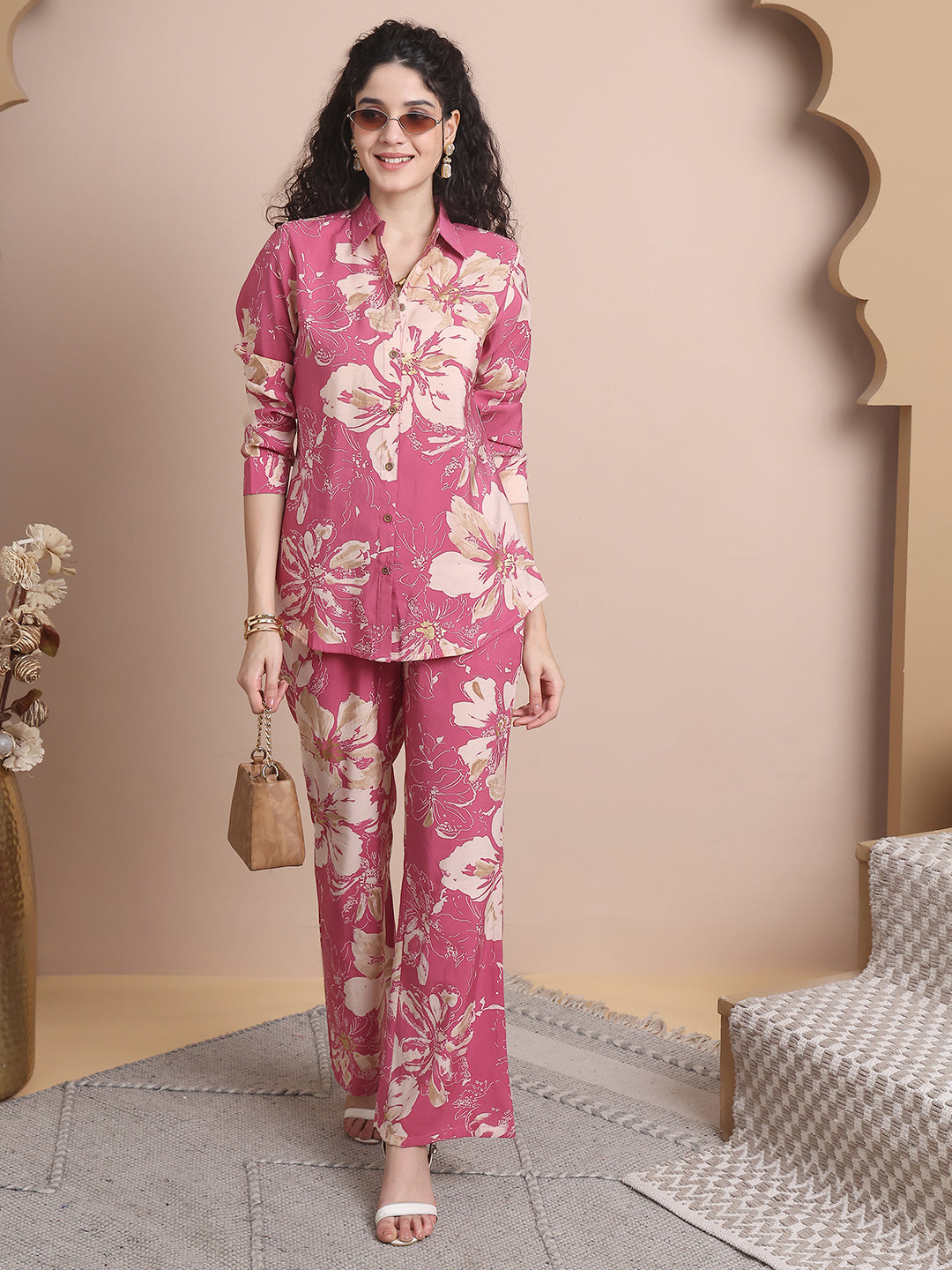 Woman wearing a pink floral outfit standing in a room with a decorative archway.